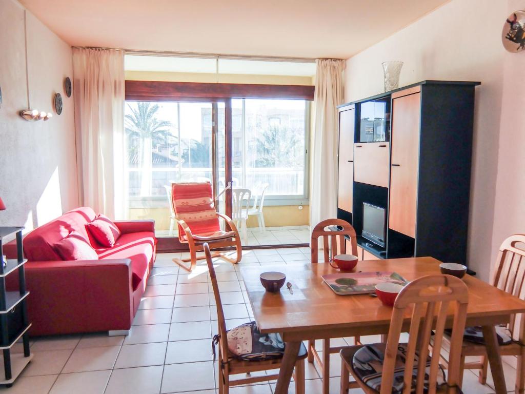 un salon avec une table et un canapé rouge dans l'établissement Apartment Les Albères by Interhome, à Saint Cyprien Plage
