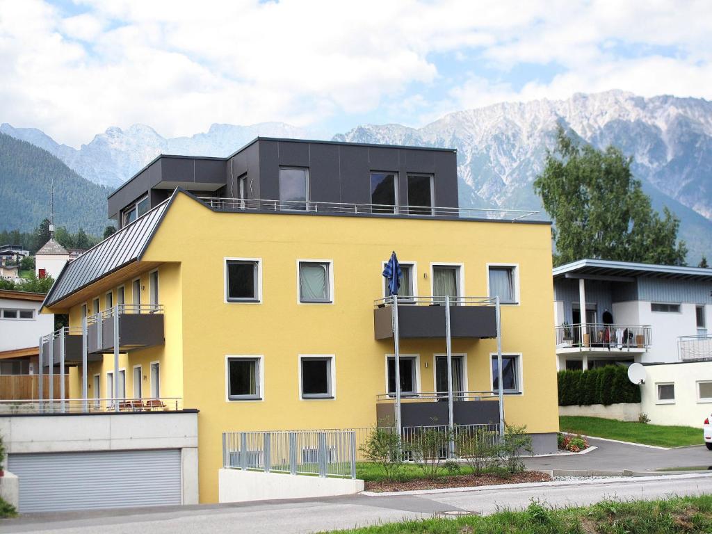 a yellow house with mountains in the background at Apartment Edith - IST100 by Interhome in Imst