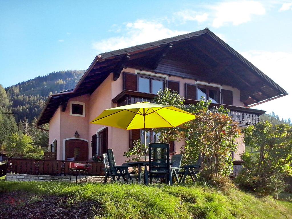 a table with a yellow umbrella in front of a house at Holiday Home Lux - STS260 by Interhome in Öblarn