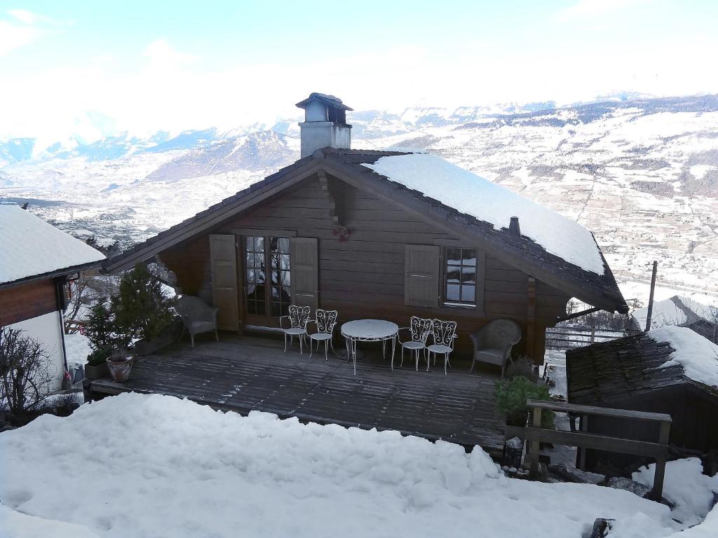 eine Blockhütte mit einem Tisch und Stühlen im Schnee in der Unterkunft Chalet Gillioz by Interhome in Vercorin