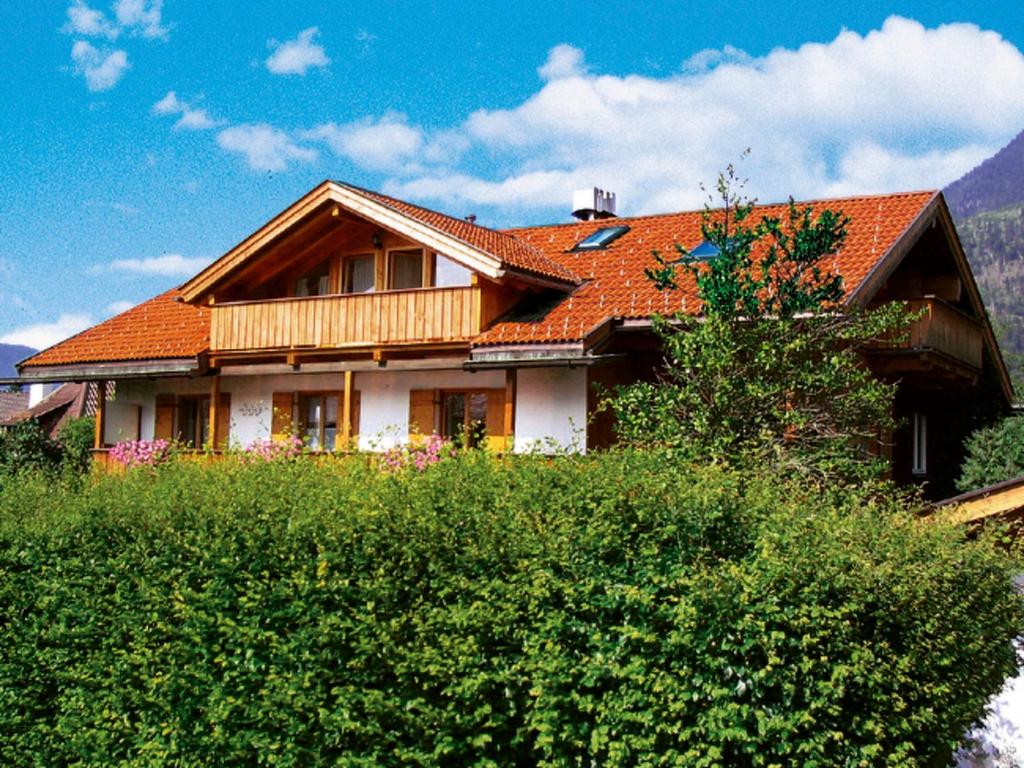 ガルミッシュ・パルテンキルヒェンにあるApartment Eberhorn by Interhomeのオレンジ色の屋根と茂みのある家