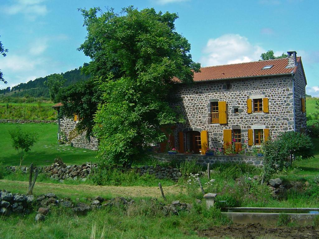 una casa de piedra con un árbol delante en Holiday Home ferme by Interhome en Agizoux