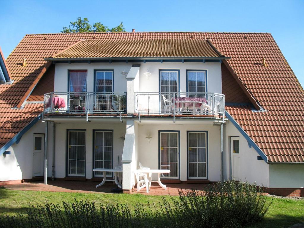 Cette maison blanche dispose d'un balcon et d'une table. dans l'établissement Apartment Gartenstraße-2 by Interhome, à Karlshagen