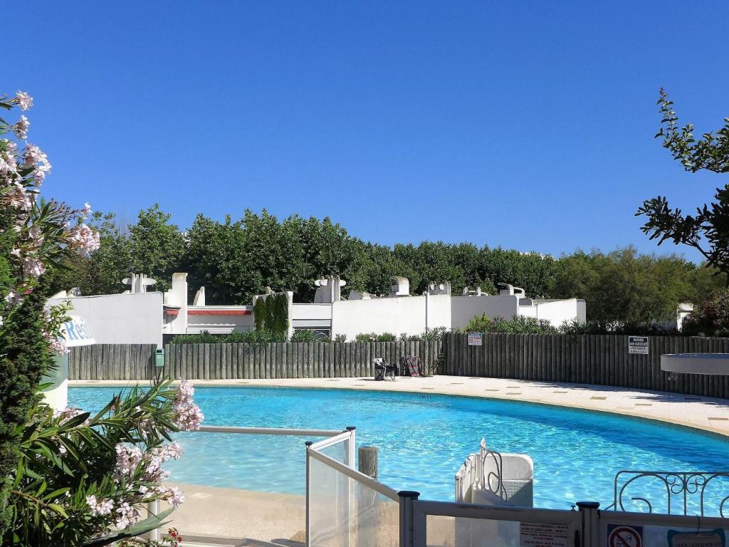 a large blue swimming pool with a fence at Apartment Du Soleil-3 by Interhome in La Grande Motte