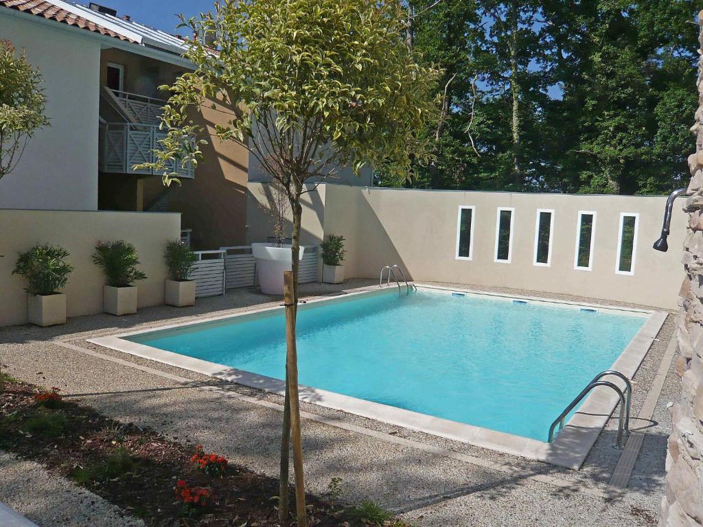 uma piscina com uma árvore em frente a uma casa em Apartment Les Demeures de Brindos by Interhome em Anglet