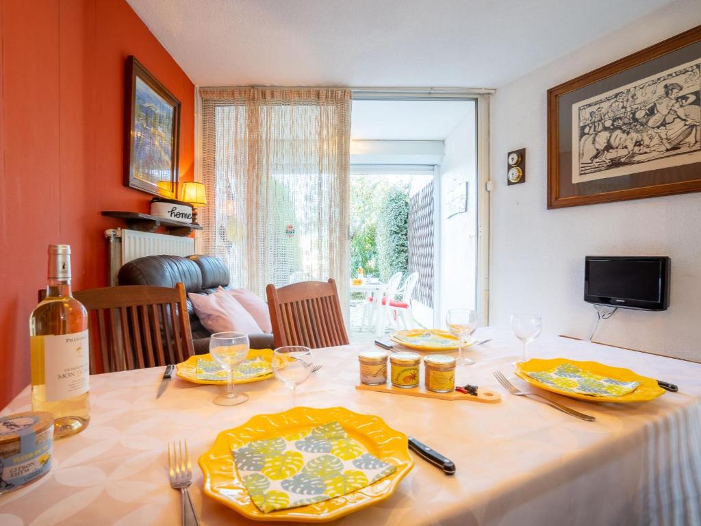una mesa de comedor con platos amarillos y una botella de vino en Holiday Home Port Nautile-1 by Interhome, en Le Grau-du-Roi
