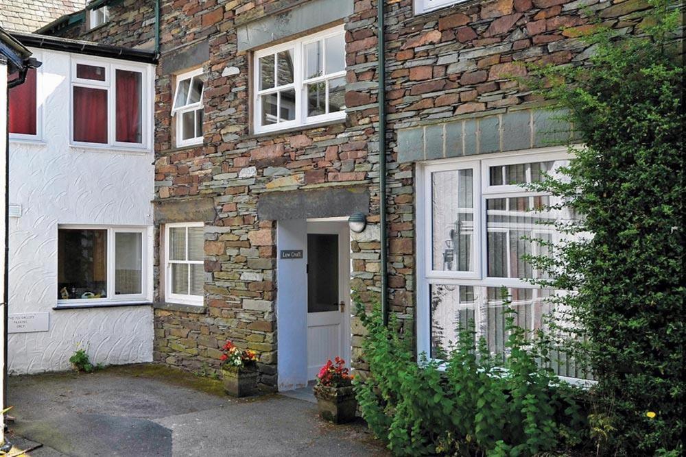 a brick house with a blue door and windows at Low Croft Cottage in Grasmere