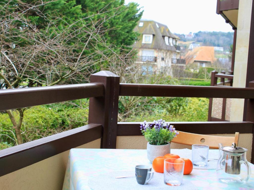 une table avec des oranges et des fleurs sur un balcon dans l'établissement Apartment Le Fairway-1 by Interhome, à Deauville