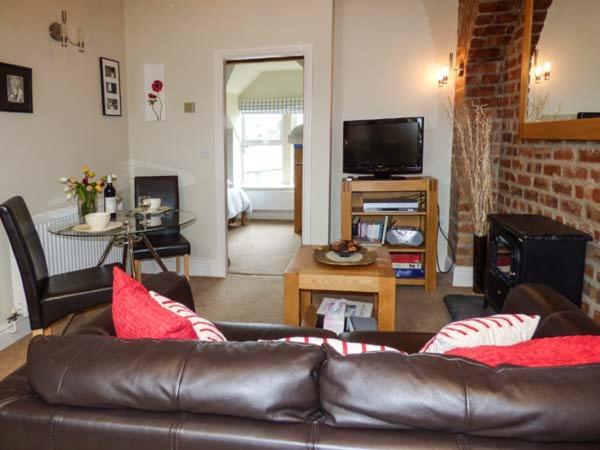 een woonkamer met een bruine leren bank en een tv bij Bluebird Loft in Coniston