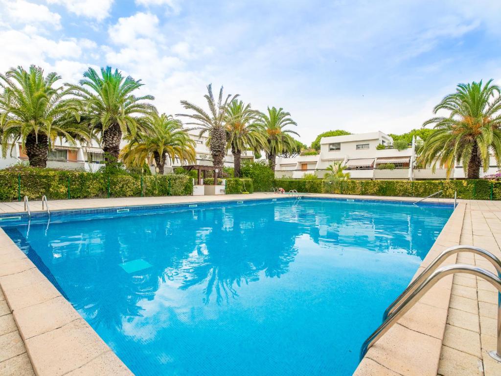 une grande piscine avec des palmiers et un bâtiment dans l'établissement Apartment Les Cyprianes-3 by Interhome, à La Grande Motte