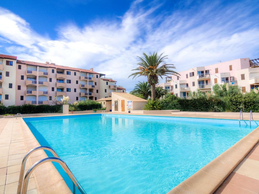 una grande piscina di fronte ad alcuni condomini di Apartment Les Capitelles by Interhome a Saint-Cyprien-Plage