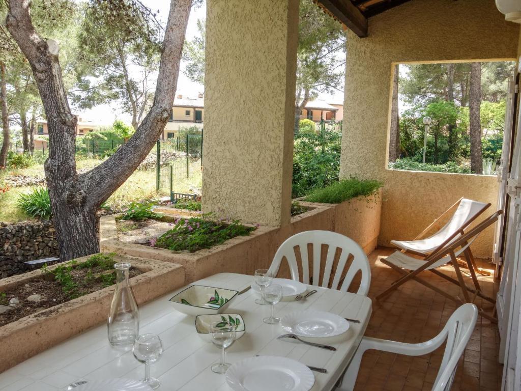 une table et des chaises blanches sur une terrasse couverte avec un arbre dans l'établissement Apartment Super Ile Rousse by Interhome, à Bandol