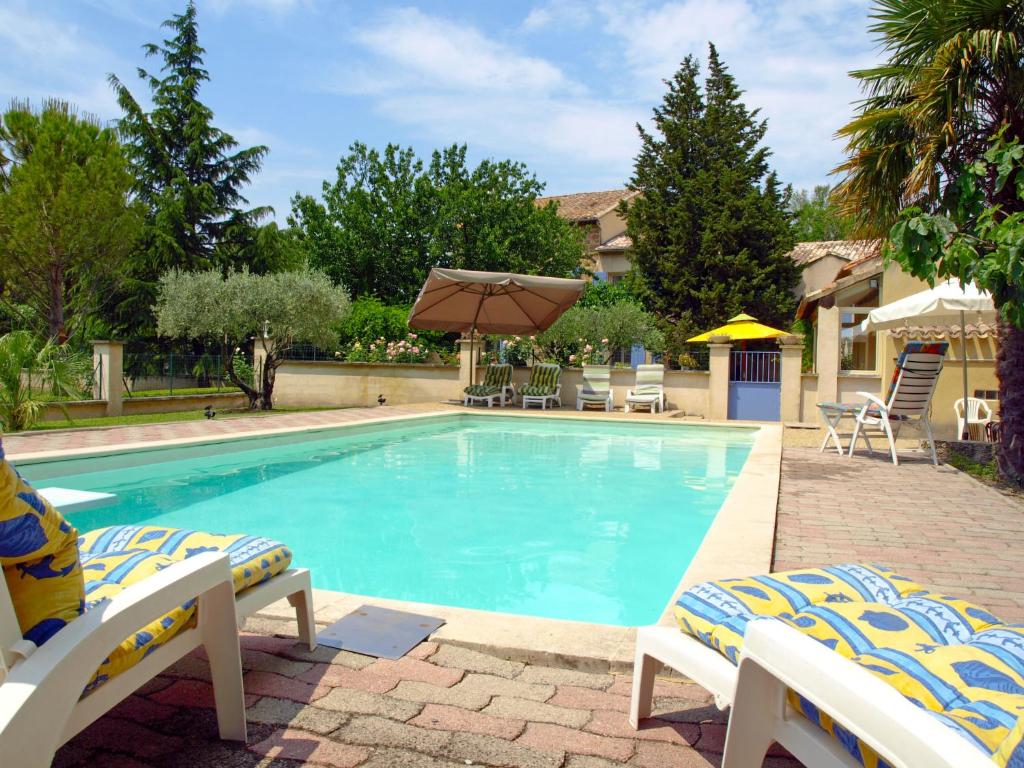 a swimming pool with two chairs and an umbrella at Holiday Home de la Roque by Interhome in Althen-des-Paluds