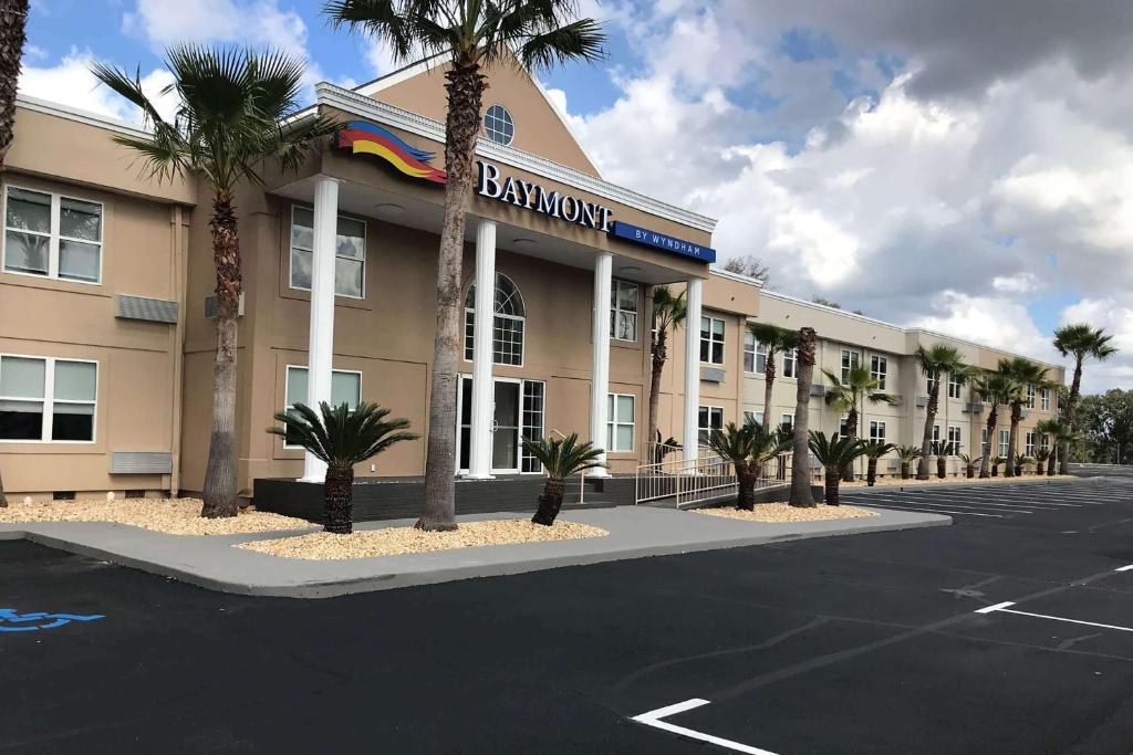 a building with palm trees in front of a parking lot at Baymont by Wyndham Lake Park Valdosta I75 in Lake Park