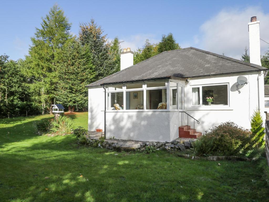 une petite maison blanche dans une cour dans l'établissement St Aethans, à Inveran