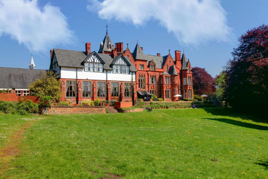 a large house with a green lawn in front of it at Bestwood Lodge Hotel in Nottingham