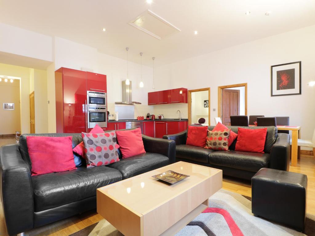 a living room with a black leather couch and red pillows at Keswick Loft in Keswick