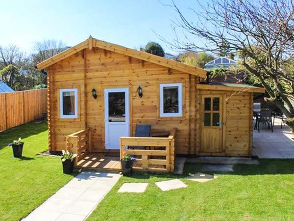 een grote houten hut met een veranda in een tuin bij Aurora Skies in Cresswell