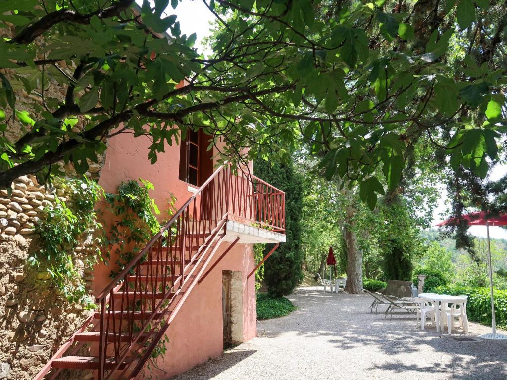 een roze gebouw met een trap en tafels en stoelen bij Holiday Home La Chênaie - ORN309 by Interhome in Oraison