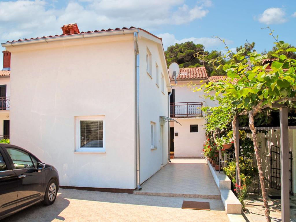 een wit huis met een auto ernaast geparkeerd bij Holiday Home Anea - PRC201 by Interhome in Poreč
