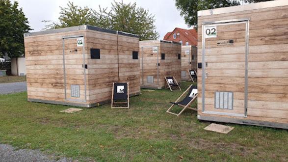 una fila de cabañas de madera con sillas en el césped en Hannover Messe Camp, en Hannover