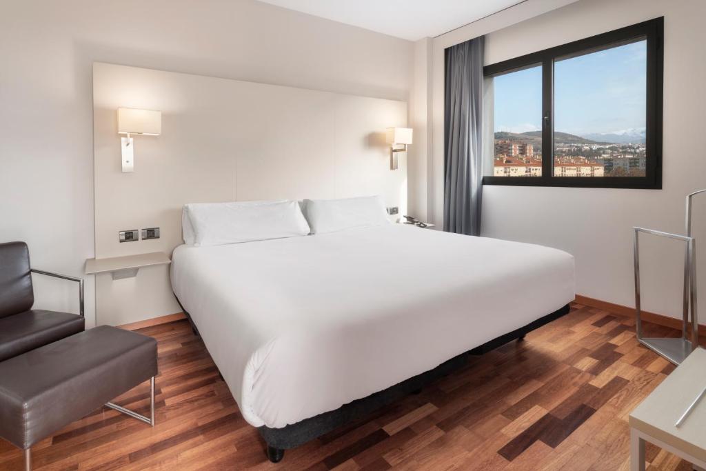Un dormitorio con una gran cama blanca y una ventana en B&B HOTEL Granada Estación en Granada