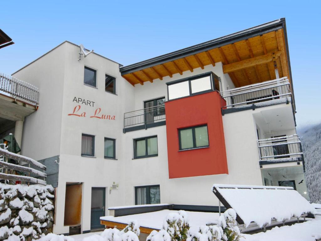 a white and red building with snow on the ground at Apartment La Luna by Interhome in Kappl