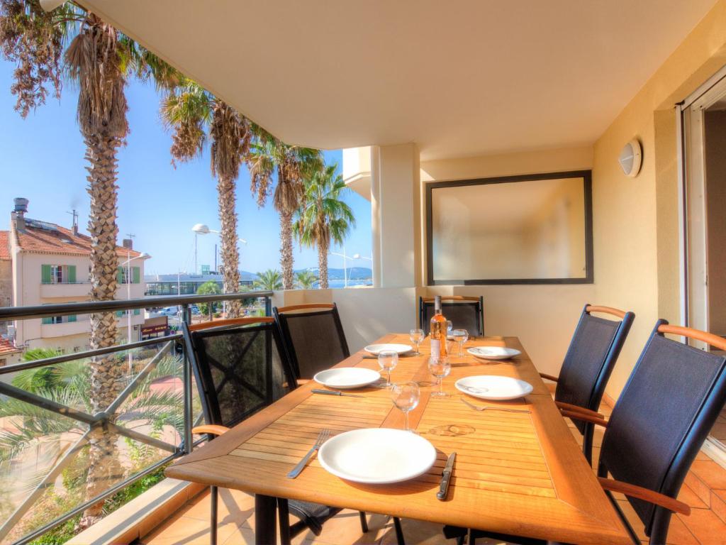 a dining room with a table and a balcony with palm trees at Apartment Le Magellan-2 by Interhome in Saint-Raphaël