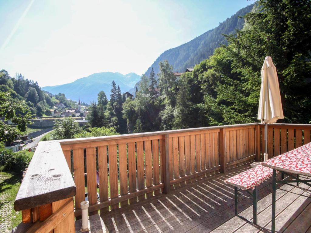 a wooden deck with a table and an umbrella at Chalet am Arlberg by Interhome in Strengen