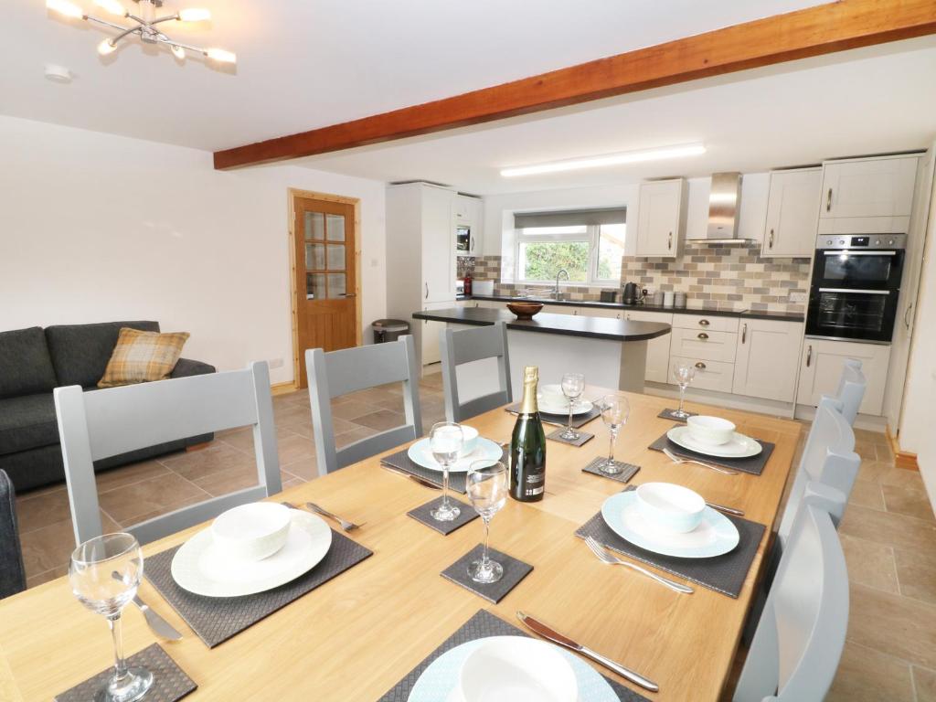 comedor y cocina con mesa de madera y sillas en Ysgubor Fawr, en Caernarfon