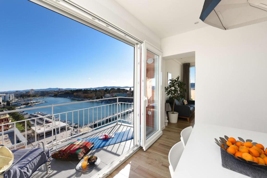 ein Wohnzimmer mit einem Balkon mit Blick auf das Wasser in der Unterkunft Penthouse Dolcevita in Zadar