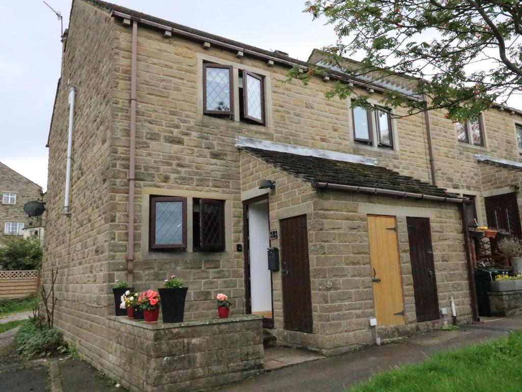 a brick house with a brown door and windows at Changegate Cottage in Keighley