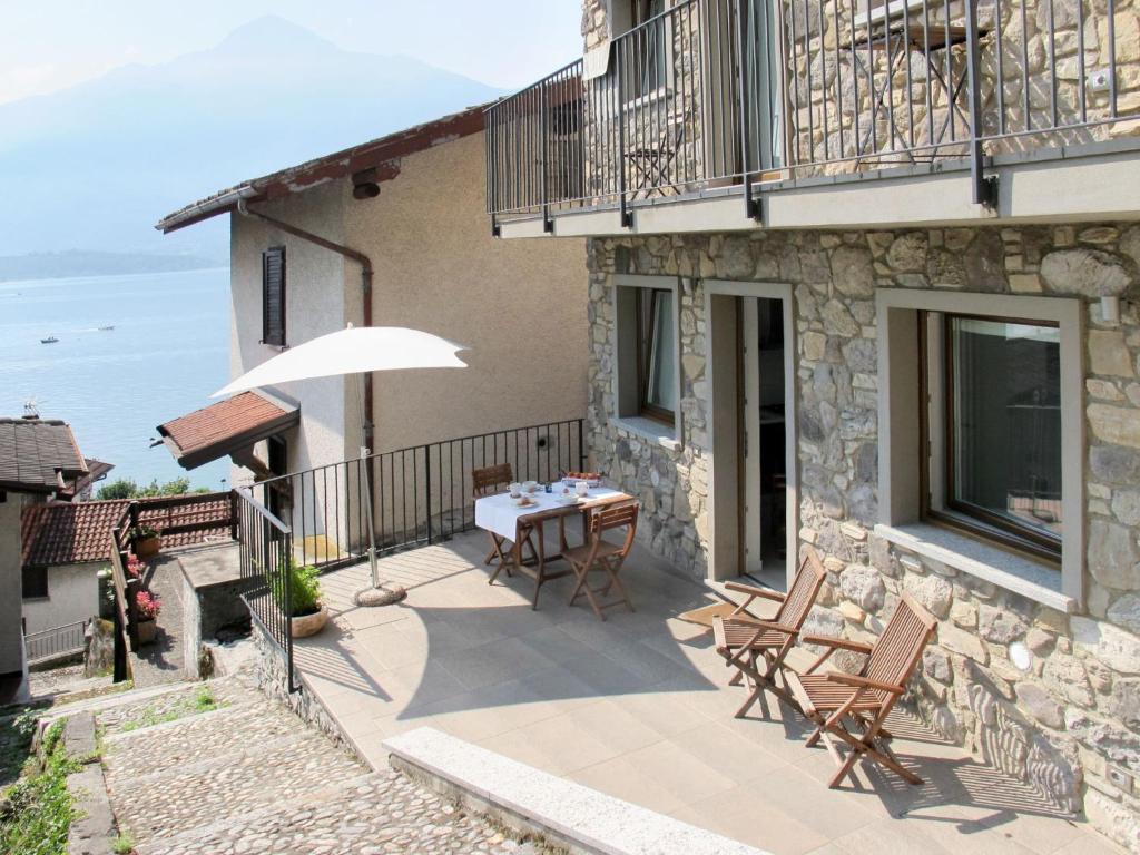 eine Terrasse mit einem Tisch, Stühlen und einem Sonnenschirm in der Unterkunft Apartment Titti - GLA133 by Interhome in Gera Lario