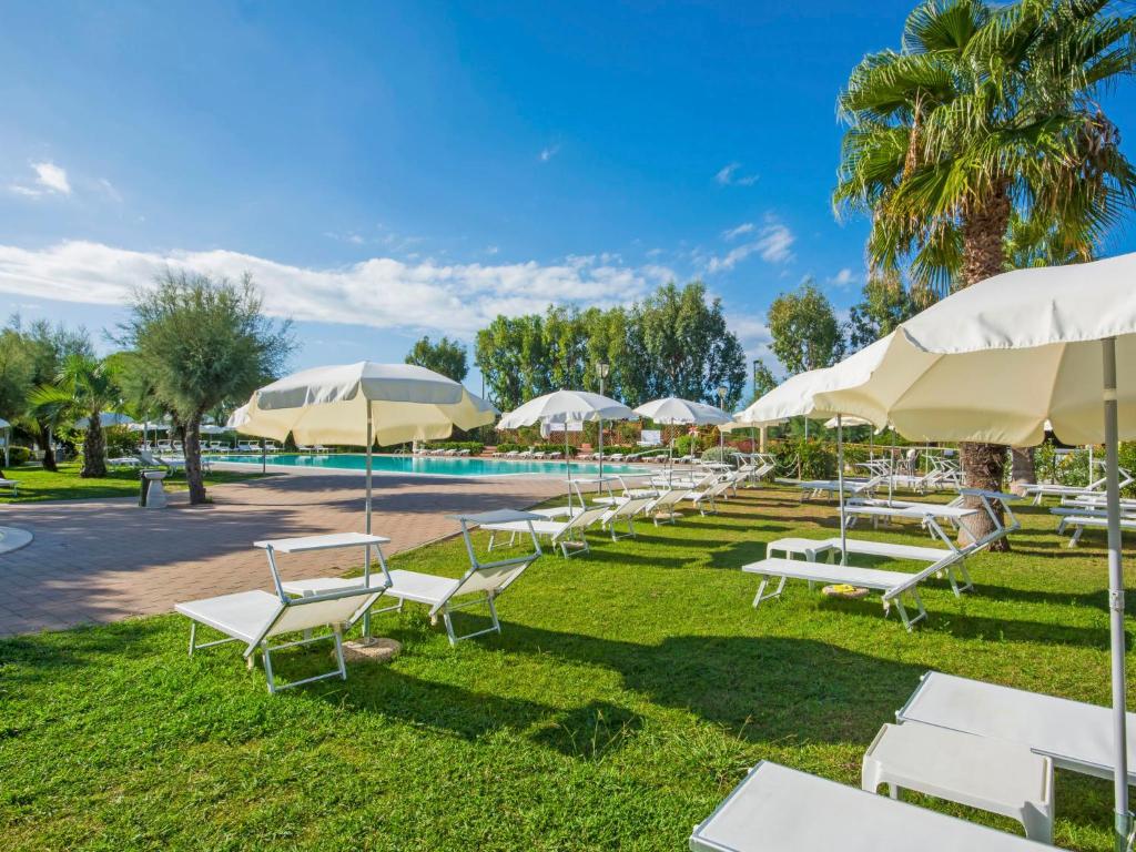 a row of white lounge chairs and umbrellas at Holiday Home Cecina Mare-11 by Interhome in Marina di Cecina