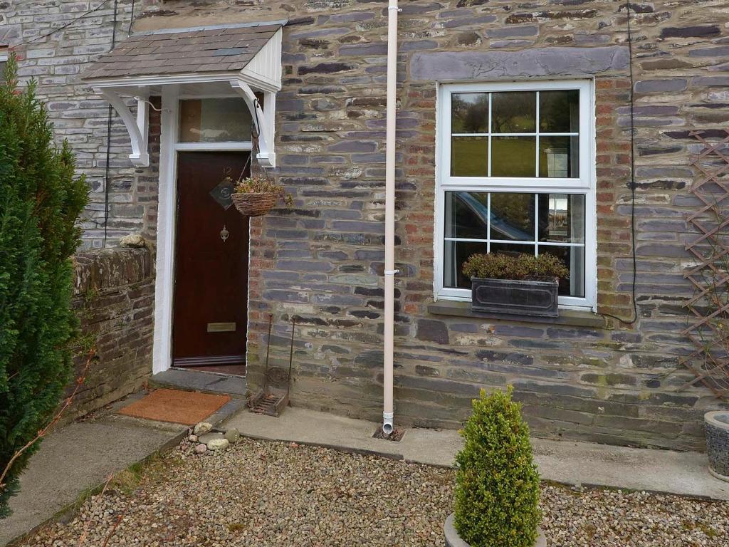 a stone house with a door and a window at 12 Victoria Terrace in Nantlle