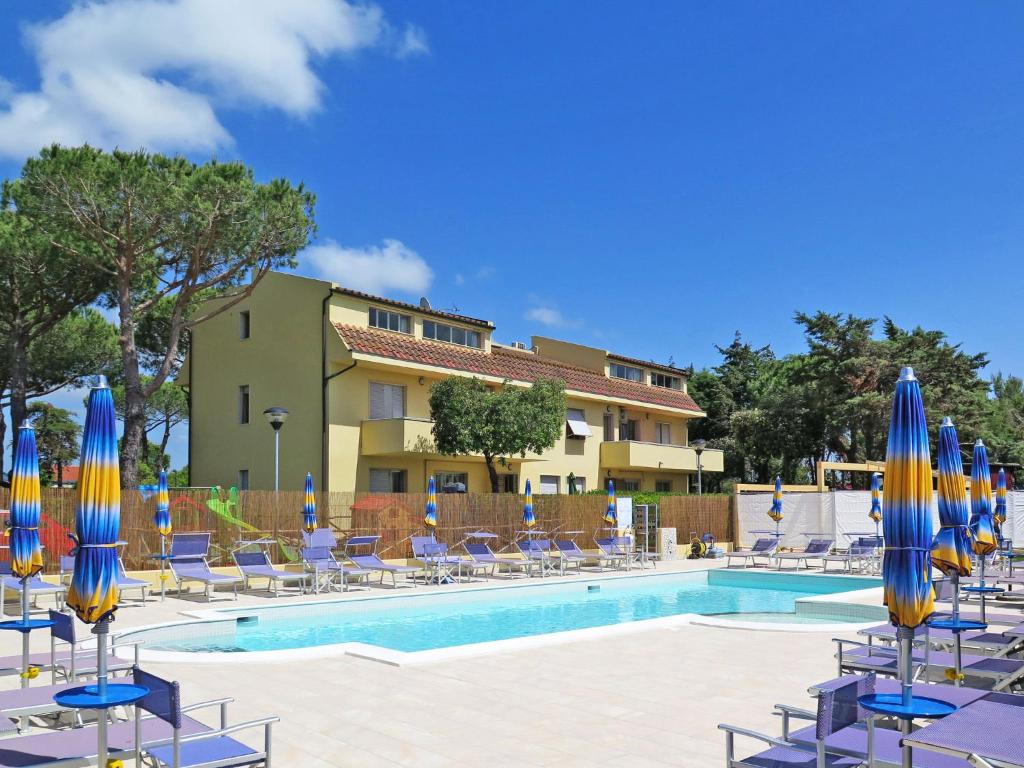 ein Pool mit blauen und gelben Sonnenschirmen und Stühlen in der Unterkunft Apartment Riviera 9 by Interhome in Marina di Cecina