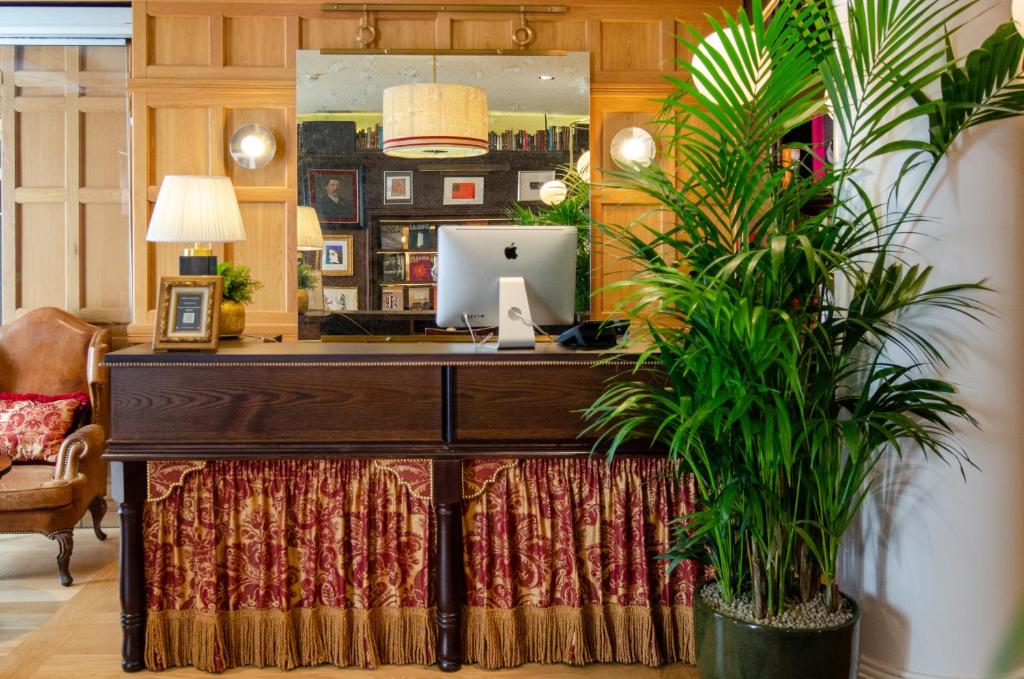 A decorative hotel work counter with an iMac, lamps and a large potted palm.