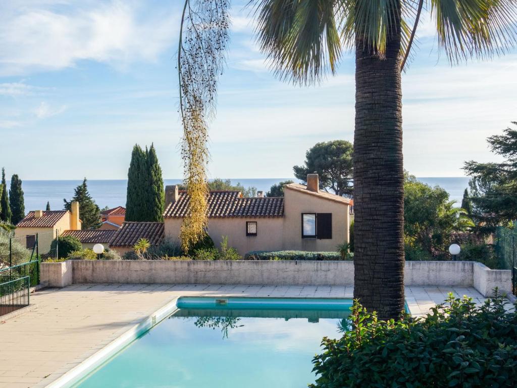 a swimming pool in front of a house with a palm tree at Studio Le Bali-1 by Interhome in La Ciotat
