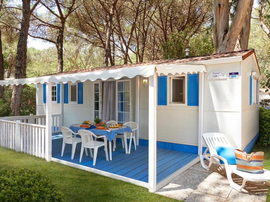 a blue and white shed with a table on a deck at Holiday Home Maxi Caravan Comfort by Interhome in Baia Domizia