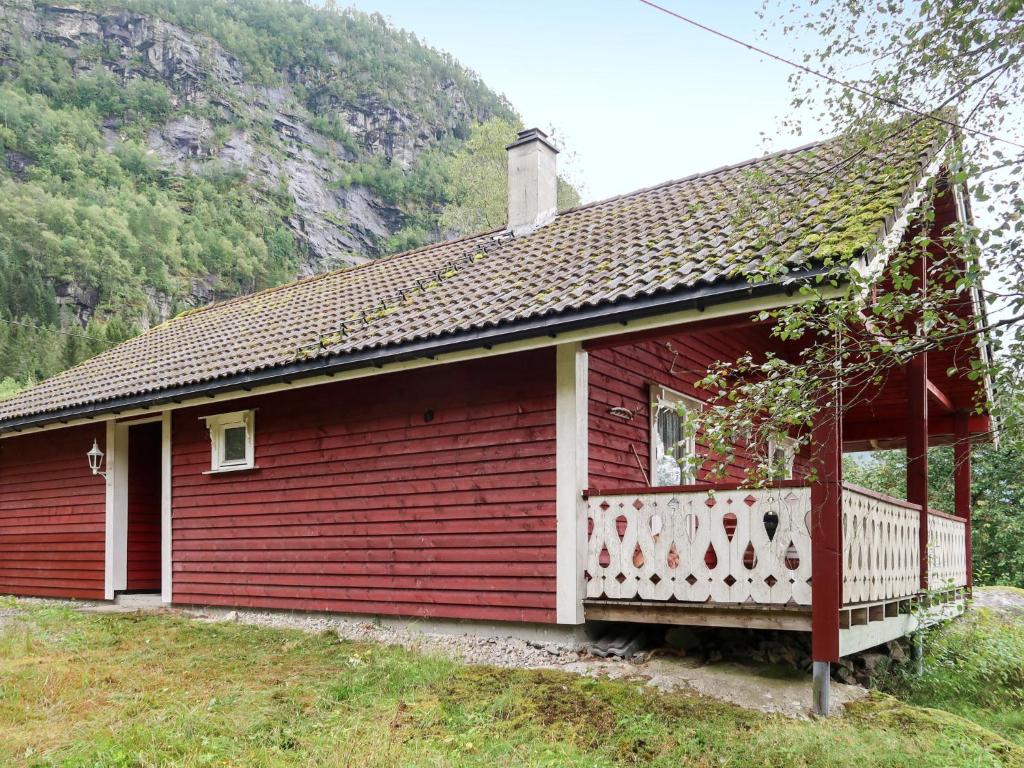 a red house with a white porch and a mountain at Chalet Revebjella - FJS086 by Interhome in Viksdalen