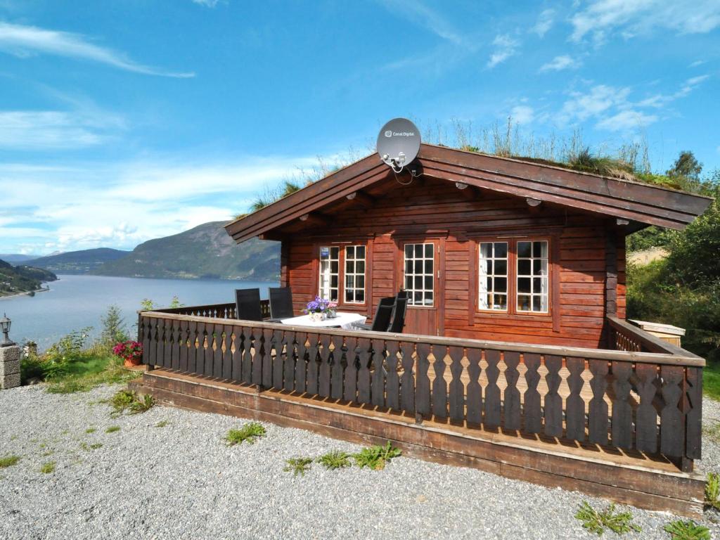 a small log cabin with a large balcony and a lake at Chalet Fjordblick I - FJS311 by Interhome in Olden