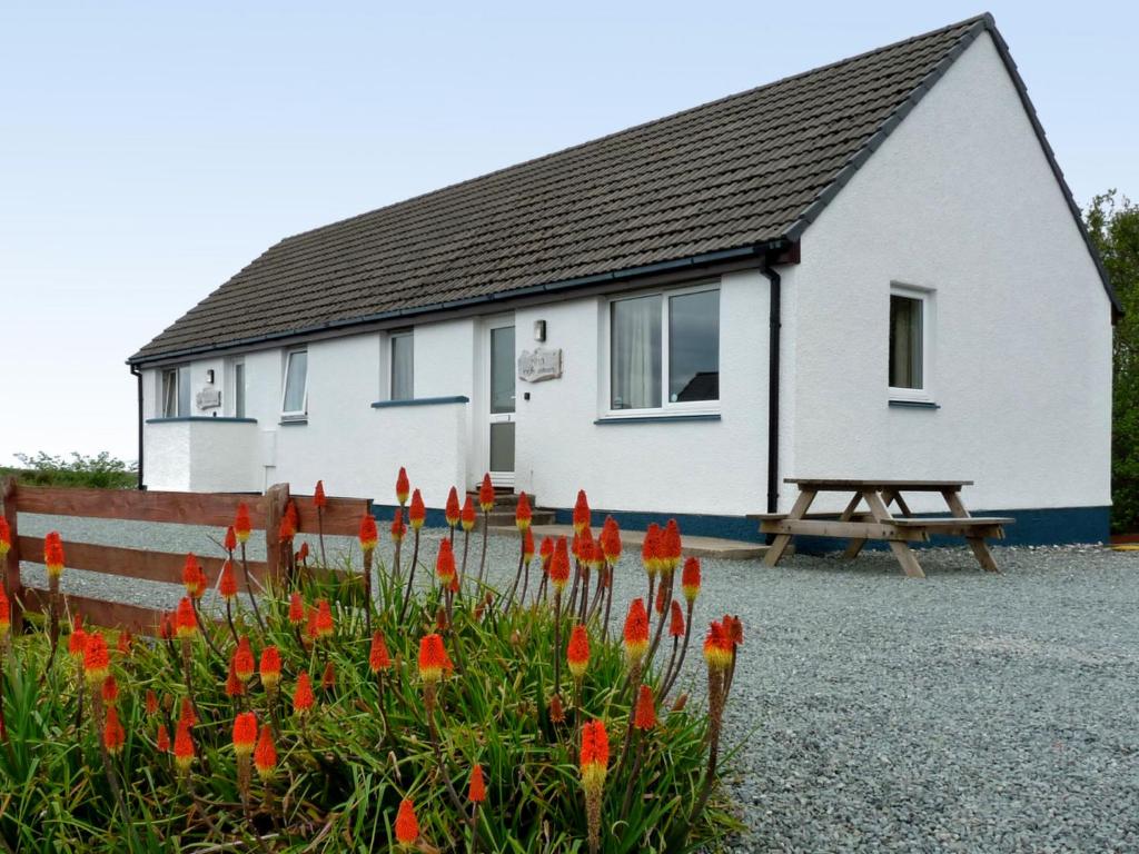 una casa blanca con una mesa de picnic y flores en Holiday Home Alan's House by Interhome, en Staffin