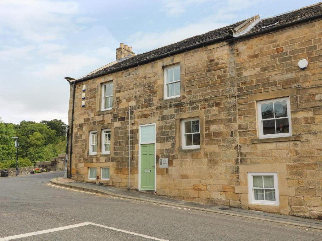 a brick building with a green door on a street at 2 Riverside in Barnard Castle