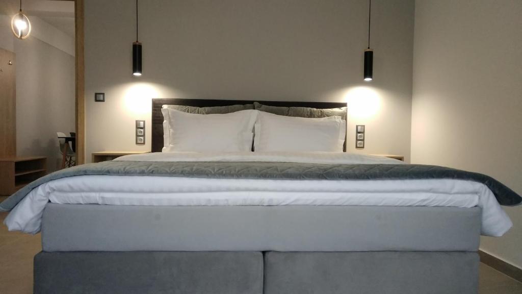 a bedroom with a large white bed with two lights at Psammites in Kalabaka