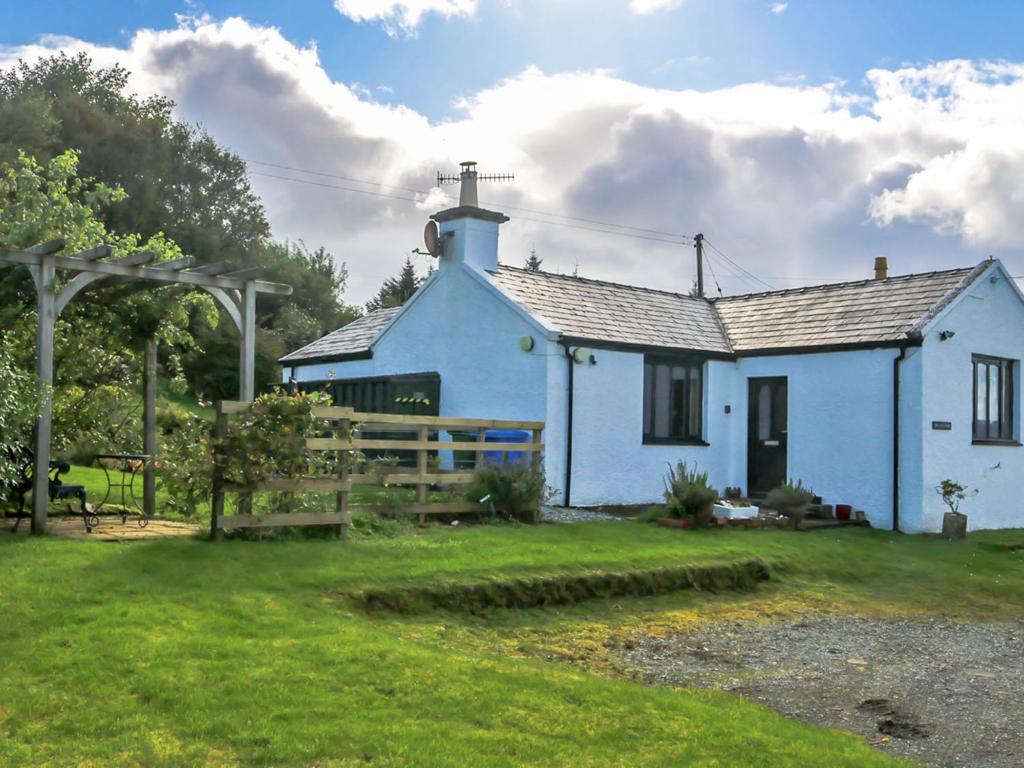 a blue house with a grass yard in front of it at Holiday Home Fiskavaig by Interhome in Fiskavaig