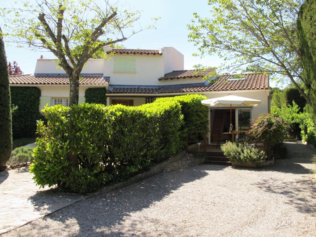 ヴィルヌーヴ・レ・ザヴィニョンにあるHoliday Home L'Oasis provencale - AVI120 by Interhomeの傘と茂みのある白い家