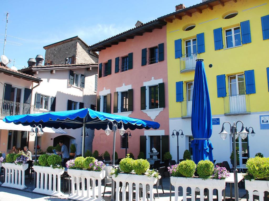 eine Terrasse mit einem Sonnenschirm und Stühlen sowie ein Gebäude in der Unterkunft Holiday Home Patrizierhaus Roncaioli by Interhome in Brusino Arsizio