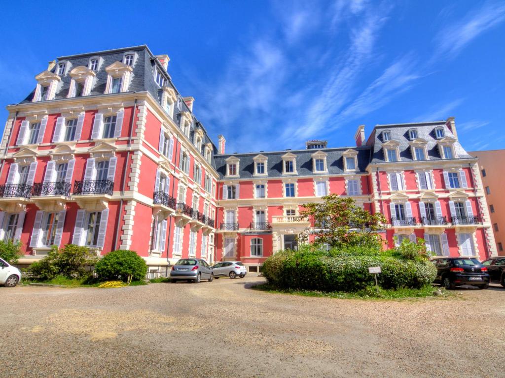 a large red building with cars parked in front of it at Apartment Reine Victoria by Interhome in Biarritz