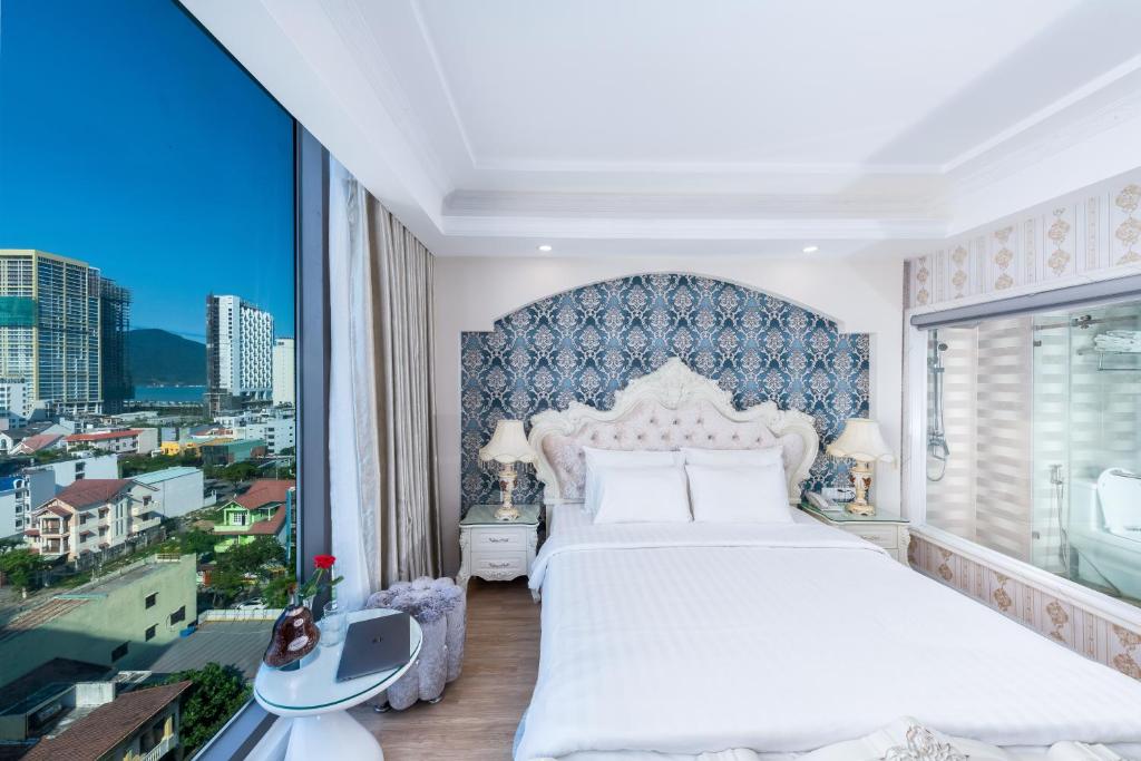 a bedroom with a white bed and a large window at Golden Rose Hotel by THG in Da Nang