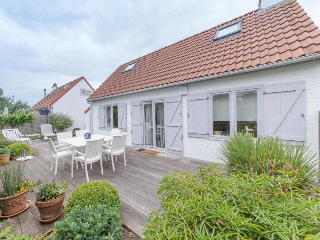 a house with a wooden deck with a table and chairs at Holiday Home New Village Park-1 by Interhome in Bredene